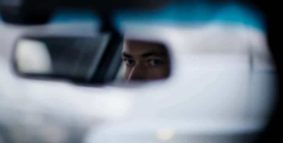Man looking in the rear view mirror while driving