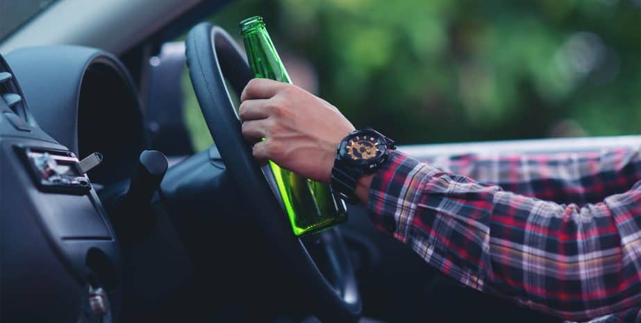 Hakiminjurylaw: asian-man-holds-beer-bottle-while-is-driving-car